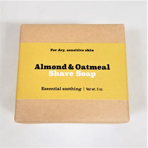 Almond and oatmeal shave soap flat in its natural wrapping with mustard-colored label in center.