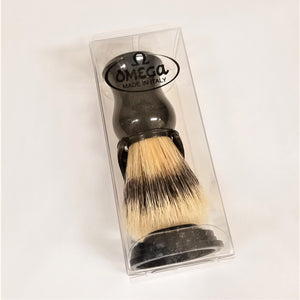 Shaving brush seen through clear plastic packaging. Brush is in the black stand with black handle on top of the natural and black bristles which are pointing down toward the bottom of the black stand.