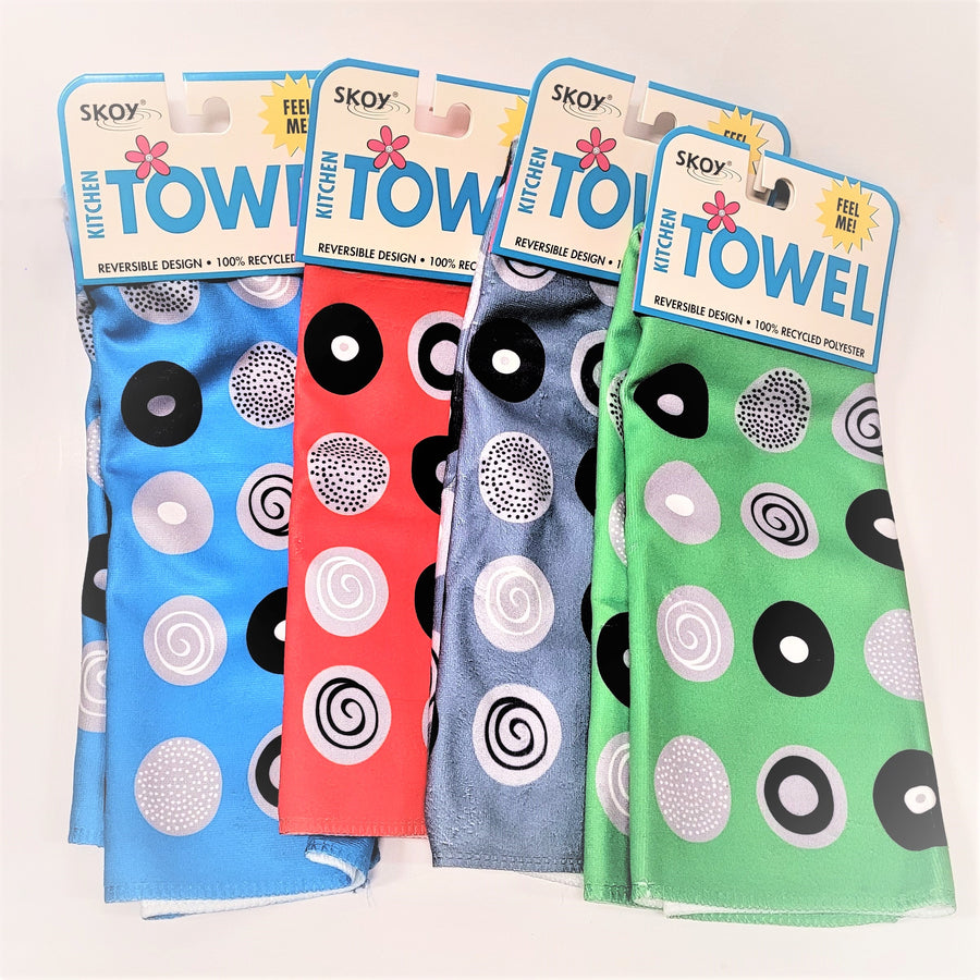 Four Skoy dishtowels fanned out with package label on top.  Each has a circle pattern with different designs within the white and black circles. Left to right: light blue, red, pale gray, light green