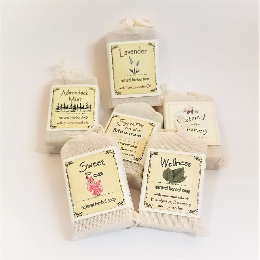 Six packages of bar soap in faux canvas bags with paper labels for each variety of soap