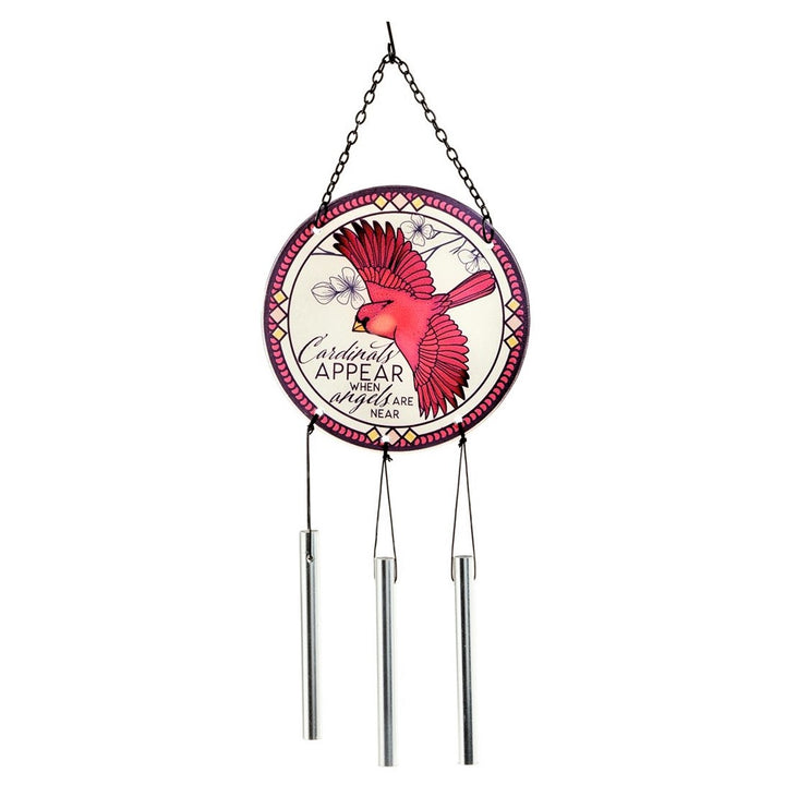 Hanging from a metal chain is a round clear sphere with a red cardinal with open wings in the center, red geometric edging around the sphere the words Cardinals appear when angels are near are printed below the beak and next to the lower wing. 3 silver wind chimes hang from the sphere vertically.