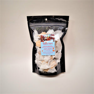 Bag of wrapped taffy. Bag has black border with clear plastic center with individually wrapped maple taffys showing through around the blue company label with maple sugaring camp depicted on the top.
