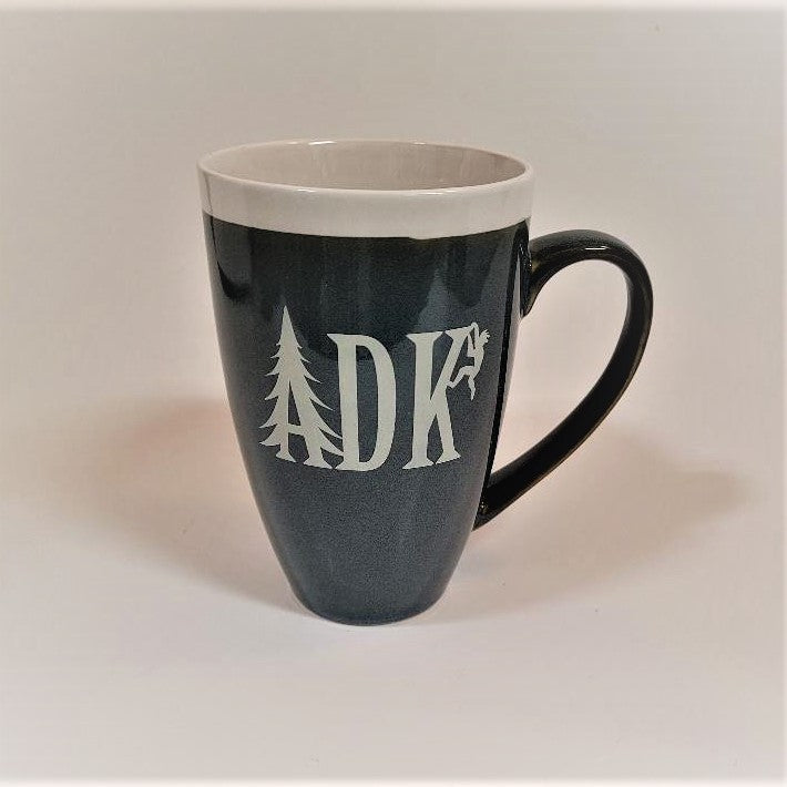 Tall slate blue mug with whie stripe around the top with white imprint featuring the letters ADK with the A in the style of a pine tree and a small hiker climbing the top of the K. Extra large handle visible on the right side.
