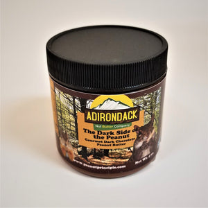 The Dark Side of the Peanut gourmet peanut butter in its plastic jar with a black screw lid. Chipmunks and forest are featured on the label surrounding the type.
