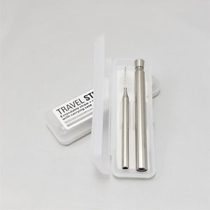 Open plastic travel straw kit leaning on a closed kit. Cleaner to the left, metal, expandable travel straw to the right.