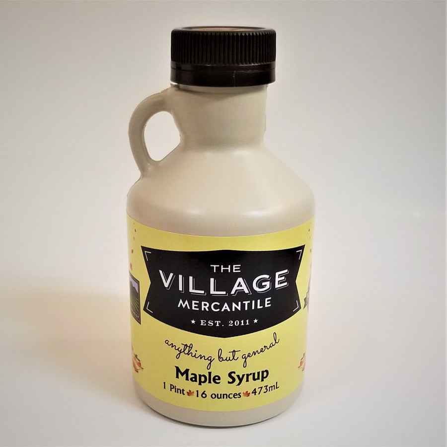 Pint-size maple syrup jug. Solid jug with handle on the left, black screw top and The Village Mercantile label bottom, mid-section.