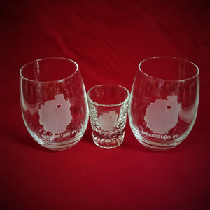 Wine Glasses and shot glass with the outline of the Adirondack Park and a heart where Saranac Lake is and the words Saranac Lake, NY etched below. All on a red background to make the etching stand out.