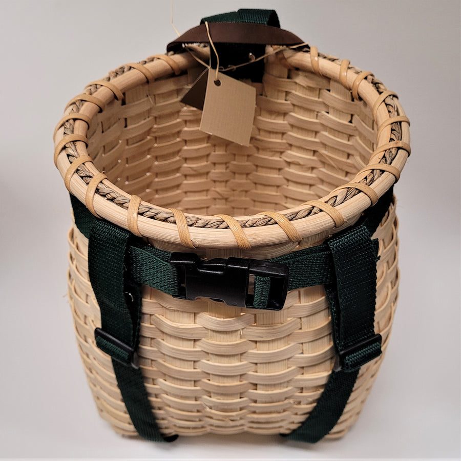 Looking inside the youth pack basket with the natural-colored weave inside, dark green straps encircling the outside, also a natural-colored weave.