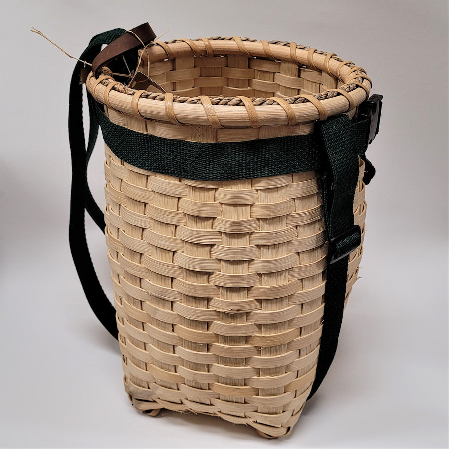 Side view of youth pack basket with green straps encircling the natural-colored woven basket.